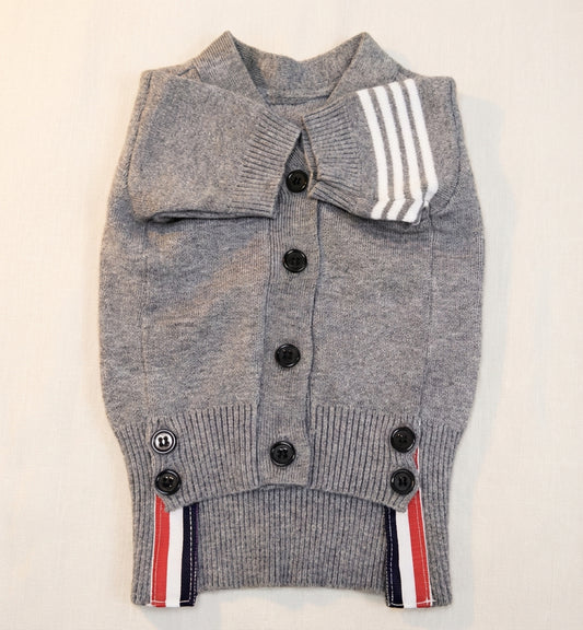 グレーのニットカーディガン（PetoPop製）、クラシックなトリコロールストライプと黒いボタンが特徴