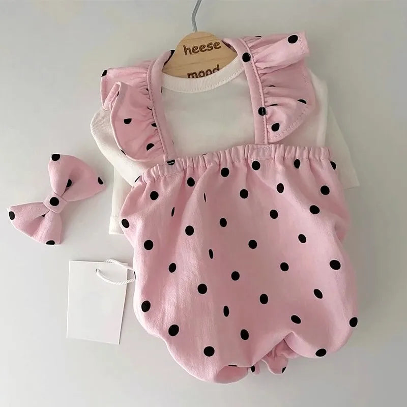Pink polka-dot cotton pet dress with ruffled straps by PetoPop, shown with matching bow and white undershirt, flat lay view