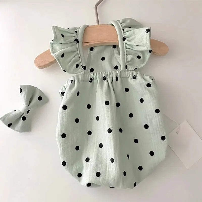 Light green polka dot pet dress by PetoPop with ruffled straps and matching bow, displayed on wooden hanger, front view