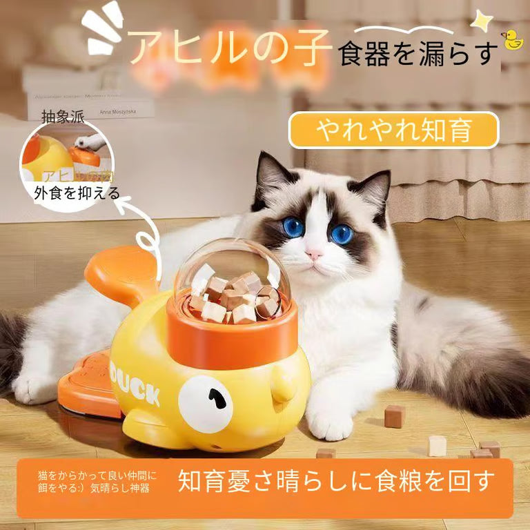 犬用インタラクティブトイ、Petopop製、黄色いアヒル型、猫が横に寝転んで、犬用おやつを見ている