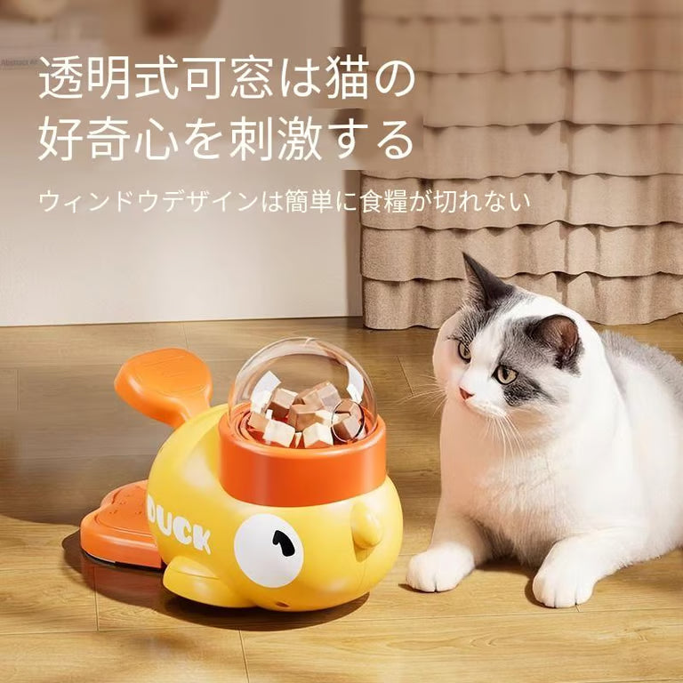 黄色いペット用おやつディスペンサー Petopop製、おやつが見える透明ドーム付き、猫が横にいる